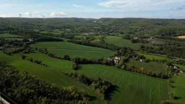 Dağlardaki tünele akan yüksek üstgeçitteki yüksek hızlı trenlerin panoramik görüntüsü. Arka planda yeşil enerji üreten bir rüzgar çiftliği var. Bir İHA 'dan Uçuş