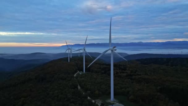 日の出と谷の厚さの朝の霧の間に山の中で風力タービン 緑のエネルギーを生産する風力発電所 — ストック動画