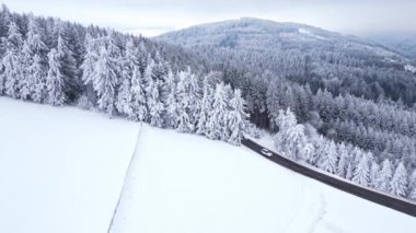 Ormandaki dağların panoramik kış drone görüntüsü. Sinematik kış karlı kırsal asfalt yolu. Karlı ormanda giden arabalar. Karla kaplı ormanlar. Sinema banliyösü manzarası.