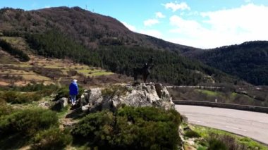 Metalden yapılmış çocuğu olan bir keçi heykeli. Col de l 'Escrinet dağının eteğinde. Genç bir kadın Col de l 'Escrinet ambleminin dibinde heykelin yanında fotoğraf çekiyor..