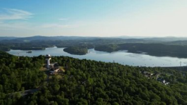 Günbatımında İHA 'nın panoramik görüntüsü Soliskie Gölü' nde Solina su barajının üstündeki gözetleme kulesine bakan modern teleferik vagonu Polonya 'nın Bieszczady Dağları' nda.