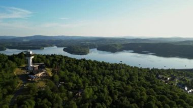 Günbatımında İHA 'nın panoramik görüntüsü Soliskie Gölü' nde Solina su barajının üstündeki gözetleme kulesine bakan modern teleferik vagonu Polonya 'nın Bieszczady Dağları' nda.