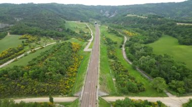 Yüksek hızlı bir yolcu treninin dağın eteğinden tünele girerken panoramik drone görüntüsü. Güney Fransa 'daki dağlara tepeden bakan