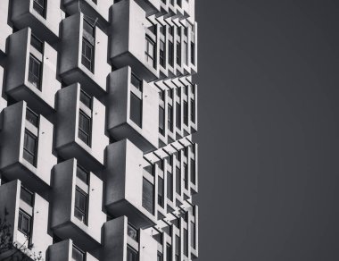 Berrak mavi gökyüzüne karşı tekrarlanan modüler balkonlarla modern geometrik daire cephesi, canlı bir şehir ortamında çağdaş kentsel mimari ve minimalist yapısal tasarımı sergiliyor