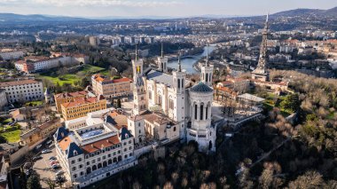 Fransa 'nın Lyon kentindeki Fourvire Hill' deki Notre-Dame de Fourvire Bazilikası 'nın hava panoramik görüntüsü, açık güneşli bir günde arka planda şehir manzarası ve metalik kule.