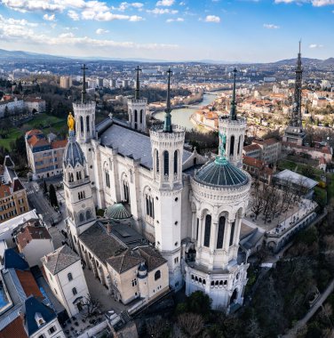 Fransa 'nın Lyon kentindeki Fourvire Hill' deki Notre-Dame de Fourvire Bazilikası 'nın hava panoramik görüntüsü, açık güneşli bir günde arka planda şehir manzarası ve metalik kule.