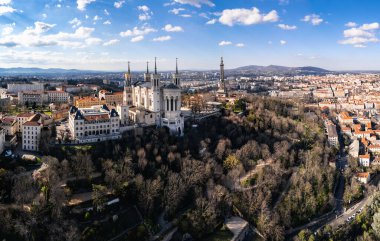 Fransa 'nın Lyon kentindeki Fourvire Hill' deki Notre-Dame de Fourvire Bazilikası 'nın hava panoramik görüntüsü, açık güneşli bir günde arka planda şehir manzarası ve metalik kule.