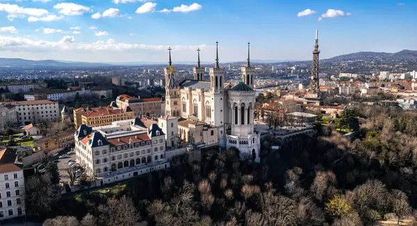 Fransa 'nın Lyon kentindeki Fourvire Hill' deki Notre-Dame de Fourvire Bazilikası 'nın hava panoramik görüntüsü, açık güneşli bir günde arka planda şehir manzarası ve metalik kule.