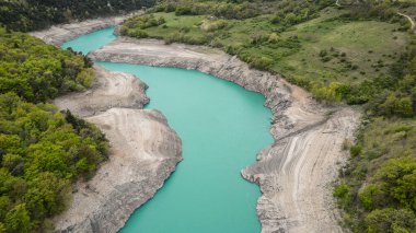 Grenoble yakınlarındaki Fransız Alplerinde Monteynard-Avignonet Gölü 'nün manzarası, alp tepeleri ve ormanlarla çevrili turkuaz dağ gölü.