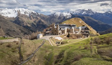 La Salette Sığınağı 'nın panoramik manzarası güneş ışığıyla yıkanmış, arka planda karla kaplı dağ zirveleri ve huzurlu bir dağlık arazi.