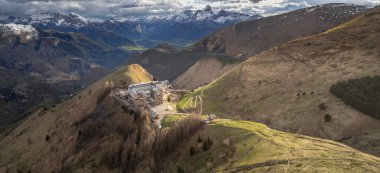 La Salette Sığınağı 'nın panoramik manzarası güneş ışığıyla yıkanmış, arka planda karla kaplı dağ zirveleri ve huzurlu bir dağlık arazi.