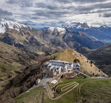 La Salette Sığınağı 'nın panoramik manzarası güneş ışığıyla yıkanmış, arka planda karla kaplı dağ zirveleri ve huzurlu bir dağlık arazi.