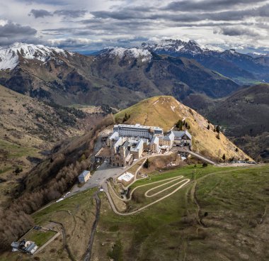 La Salette Sığınağı 'nın panoramik manzarası güneş ışığıyla yıkanmış, arka planda karla kaplı dağ zirveleri ve huzurlu bir dağlık arazi.