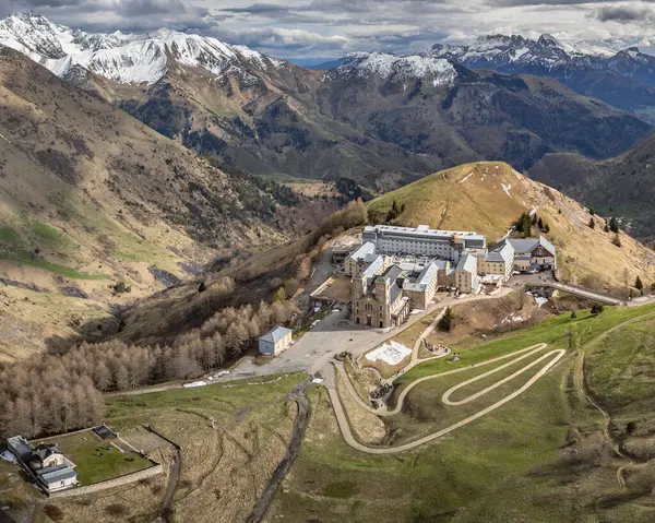 La Salette Sığınağı 'nın panoramik manzarası güneş ışığıyla yıkanmış, arka planda karla kaplı dağ zirveleri ve huzurlu bir dağlık arazi.
