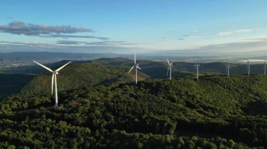 Enerji üretimi için türbin yel değirmenleri. Yenilenebilir enerji kaynakları. Ağaçlarla kaplı bir tepede bulunan yel değirmenleri. Çevredeki dağlara bakıyor. Drome - Güney Fransa