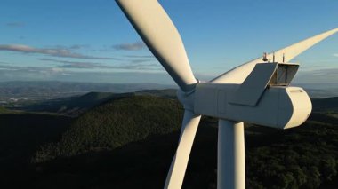Turbine windmills for energy production. Renewable energy sources. Windmills situated on a hill overgrown with trees. Overlooking the surrounding mountains.