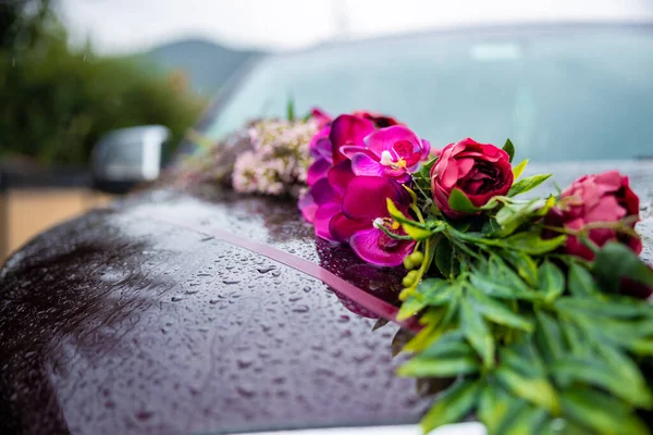 stock image Beautiful wedding car. Front of the luxury car decorated pink flowers on a rainy day. Raindrops on car. High quality photo