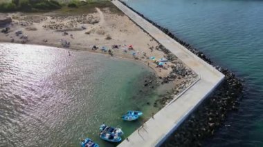 Yazın günbatımında Bulgar Karadeniz kıyısında bir plaj. Şemsiyeli insanlar. Suda bir iskele. Hava aracı görüntüsü. Yüksek kalite 4k görüntü