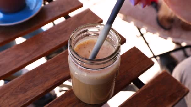 一个画指甲的女孩用生物牛奶和纸稻草搅拌着一杯冰咖啡 高质量的4K镜头 — 图库视频影像