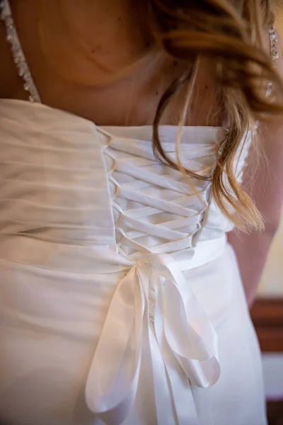 The back of a white wedding dress. The back of a bride and her hair flowing over her white gown. High quality photo