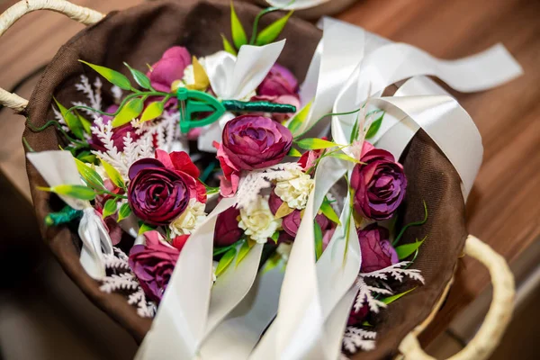 Wedding decoration. Pink and purple flower bracelets and badges in a wooden basket for the guests of the wedding. High quality photo