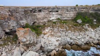 Bulgaristan 'daki mavi, yeşil, turkuaz dalgaların, manzaralı deniz kayalıklarına ve keskin kayalara çarptığı havadan insansız hava aracı görüntüleri. Yüksek kalite 4k görüntü