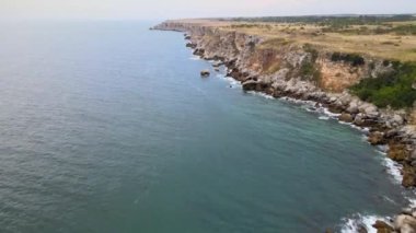 Bulgaristan 'daki mavi, yeşil, turkuaz dalgaların, manzaralı deniz kayalıklarına ve keskin kayalara çarptığı havadan insansız hava aracı görüntüleri. Yüksek kalite 4k görüntü