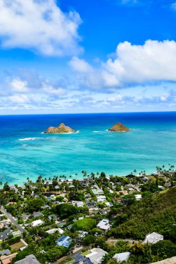 Oahu 'daki bir dağın tepesinden bir fotoğraf. Uzakta açık mavi okyanus suyu ve iki küçük ada görünüyor. Mavi bulutlu gökyüzü. Yüksek kalite fotoğraf