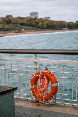 Köprüde denizde güvende olmak için turuncu bir şamandıra. Arka planda mavi deniz. - Evet. Yüksek kalite fotoğraf