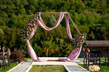 Düğün kemeri süslemesi. Bulgaristan 'ın güzel doğasında zarif bir tören. Çiçekli kemer ve pembe bez. Yüksek kalite fotoğraf