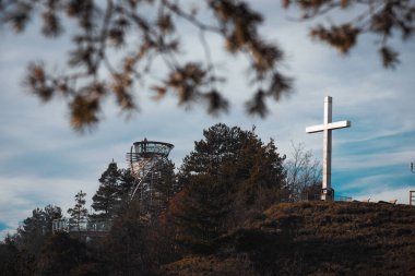 Architecture observation lookout point structure in Razlog, Bulgaria. White cross statue in Autumn winter time shot through tree branches. High quality photo clipart