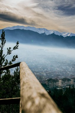 Gün batımında tahta korkuluk ve uzak arkaplanda karlı dağlar. Güzel, çarpıcı doğa çekimi. Razlog şehri, dağların altında..