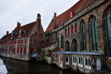 Belçika, Brugge 'deki bir nehrin arasında tuğla binalar. Kış havası, bulutlu gökyüzü. Yüksek kalite fotoğraf