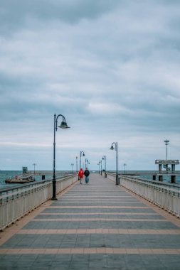Denizde bir köprüde yürüyüş yapan bir çift. Kış sonbahar sezonu. Yüksek kalite fotoğraf
