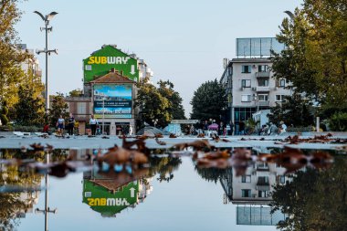 Burgaz, Bulgaristan 25,09,20: Yerdeki yağmur suyu gökyüzünü ve binaları yansıtıyor. Sonbahar yaprakları suya düştü. Yüksek kalite fotoğraf