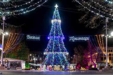 Burgaz şehir merkezinde bir Noel ağacı ve renkli ışıklar. Kelimelerin çevirisi 