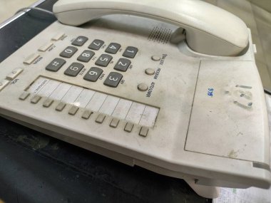Beyaz tuğlalı bir duvarın arka planında eski model bir telefon.