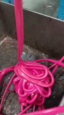Pembe kauçuk boru eritilip bir çıkarma makinesine dönüştürülüyor. Boru sarılmış ve dolanmış. Üretim sürecine benziyor.. 