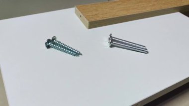 Bir adamın eli kaldırır ve beyaz bir tahta üzerine farklı vidalar yerleştirir. Reklam endüstrisi ve imalat için klip. 