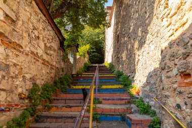 İstanbul, Türkiye - 2 Kasım 2024: Balat İlçesi 'nde renkli merdivenler ve tepe örtüsüyle dekore edilmiş taş kafenin dış gündüz çekimi