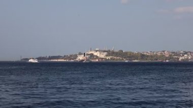 Suda birkaç tekne olan sakin bir mavi okyanus. Tekneler, bazıları kıyıya daha yakın, bazıları ise daha uzak sulara doğru dağılmış durumda. Huzurlu ve huzurlu bir sahne.
