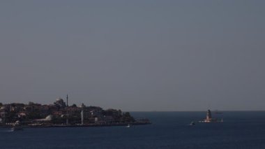 Uzakta küçük bir adası olan güzel mavi bir okyanus. Uzaklarda büyük bir gemi hareket ediyor.