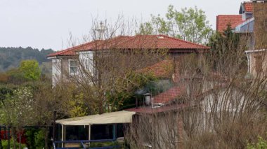 Kırmızı çatılı ve yanında beyaz bir ev olan bir ev. Beyaz Saray 'ın bacası var.