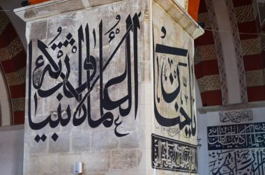 Duvar Arapça yazıyla kaplı. Yazı siyah beyaz ve çok detaylı. Yazı taş bir sütunun üzerinde.