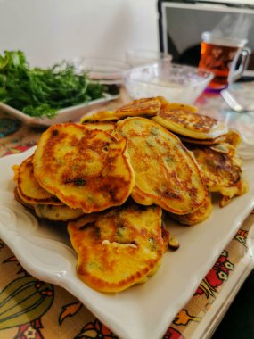 Taze bitki ve çayla birlikte beyaz tabakta ev yapımı sebzeli krep.