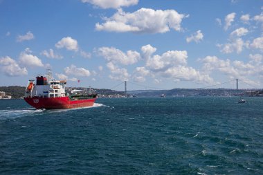 İstanbul 'da Köprü ve Bulutlu Gökyüzü ile Kırmızı Kargo Gemisi İstanbul Boğazı' ndan geçiyor