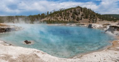 Excelsior gayzerinden dağlara doğru yayılan panoramik duman manzarası. Yaz boyunca Yellowstone Ulusal Parkı 'ndaki ormanın ortasındaki kaplıcada. Arka planda gökyüzü olan ünlü jeotermal manzara.