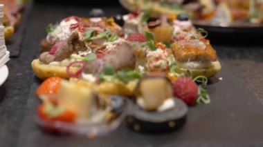 Siyah taş tabaklar üzerinde güzel kanepeler. Büfe masası. Sinema videosunda yemek servisi.