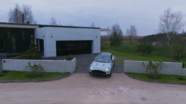 豪华汽车停泊在城外的现代私人别墅里 Aston Martin Dbx707停放在旁边的豪华私人住宅的空中视频 — 图库视频影像