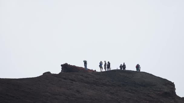 火山エトナ山をハイキングする観光客 有名な場所で冒険的な休暇を楽しんでいる人々 背景に煙に覆われた空と劇的な風景のビュー Etna — ストック動画